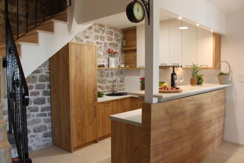 uma cozinha com armários de madeira e uma parede de pedra em Luka Villa em Bečići