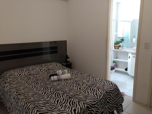 uma cama com estampa de zebra num quarto branco com em Apartamento em Cabo Frio em Cabo Frio