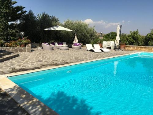 a swimming pool with lounge chairs and an umbrella at Poggio Delle Palme in Campobello di Licata