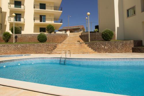 a swimming pool in front of a building with stairs at Quinta das Rosas - Oceanview Apartment in Buarcos