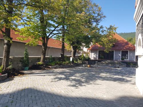 une cour avec des arbres devant un bâtiment dans l'établissement BASALTINA Panzió, à Balatonederics