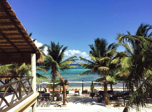 a view of a beach with chairs and palm trees at Hotel Luna De Plata in Mahahual