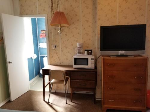 a room with a desk with a television and a microwave at Melsask Motel in Melville