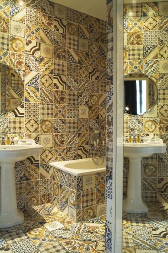 a bathroom with two sinks and a tiled wall at Hôtel du Petit Moulin, Haute Couture hotel by Lacroix in Paris