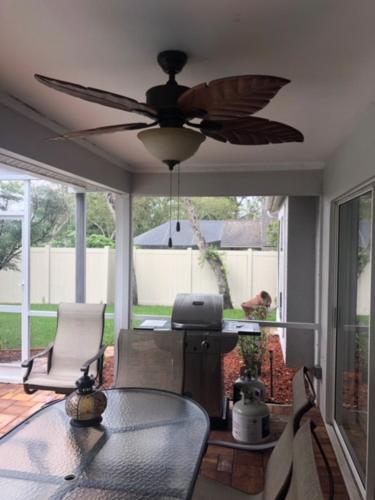 a living room with a ceiling fan and a table at Modern Pool Home in Spring Hill