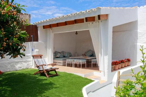 a white pergola in a garden with a chair at Es Badiu in Alaior