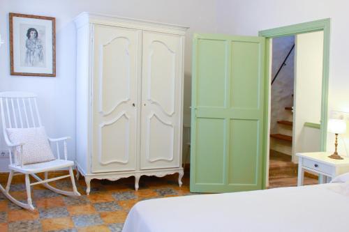 a bedroom with green and white cabinets and a chair at Es Badiu in Alaior