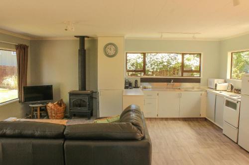 a living room with a couch and a kitchen at Naseby Cottage - 24 Leven St in Naseby