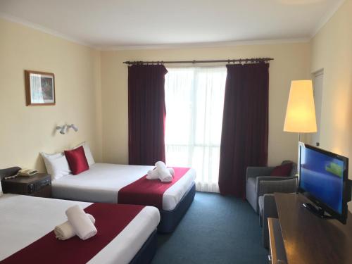 a hotel room with two beds and a flat screen tv at Australia Park Motel in Albury