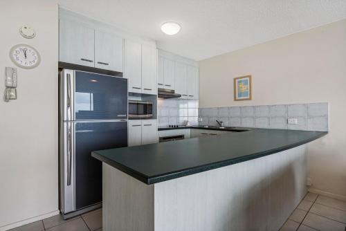 a kitchen with a black counter top and a refrigerator at Key Largo Maroochydore in Maroochydore