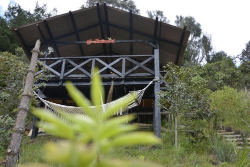 a hammock in front of a building with trees at El Pedregal Sopó in Sopó
