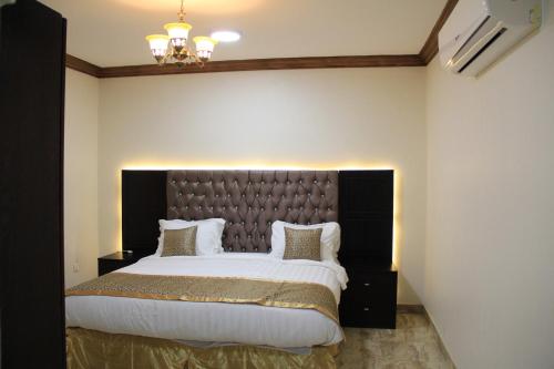 a bedroom with a large bed with a black headboard at Ahla Makan in Dammam