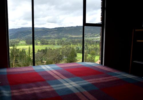 a bedroom with a view of a field from a window at El Pedregal Sopó in Sopó