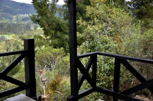 a wooden fence with trees and mountains in the background at El Pedregal Sopó in Sopó