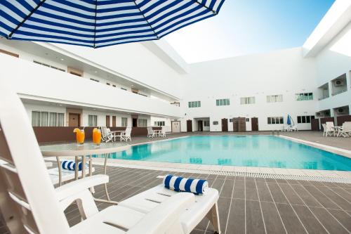 a pool in a hotel with chairs and an umbrella at Garden Sentral Hotel in Kuala Belait