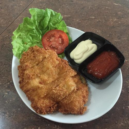 a plate of food with chicken lettuce and a tomato at Hotel Harmony In & Karaoke in Pontianak