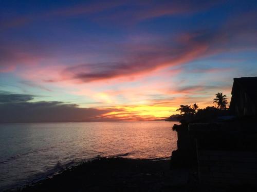 a sunset over a body of water with palm trees at Costa Cantagay in Jagna