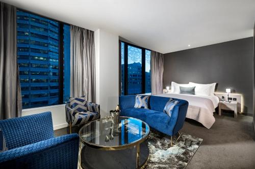 a hotel room with a king bed and blue chairs at The Melbourne Hotel in Perth