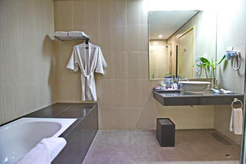 ein Badezimmer mit einer Badewanne, einem Waschbecken und einem Spiegel in der Unterkunft Padjadjaran Suites Resort and Convention Hotel in Bogor