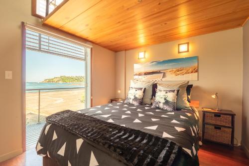 a bedroom with a bed with a view of the ocean at Absolute Beach front-Tutukaka Harbour in Tutukaka