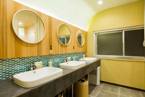 łazienka z 2 umywalkami i 2 lustrami w obiekcie Kobe Guesthouse MAYA w mieście Kobe