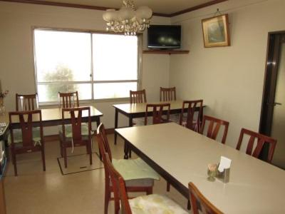 a dining room with tables and chairs and a chandelier at Aoi Business Hotel in Fukuyama