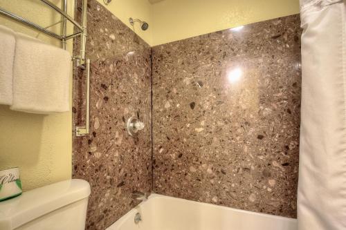 a bathroom with a shower and a tub and a toilet at Bayside Inn in Monterey