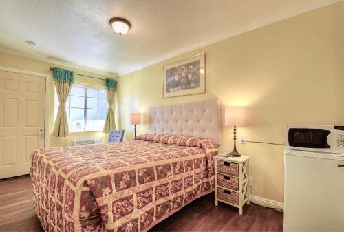 a hotel room with a bed and a microwave at Bayside Inn in Monterey