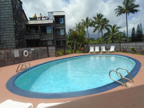 a large swimming pool with chairs and a building at Princeville Sealodge Unit D-4 in Princeville