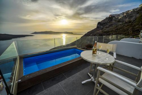 a balcony with a table and a swimming pool at Kratiras View Luxury Suites in Fira