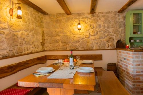 a wooden table with plates and wine glasses on it at Apartman Lidija in Makarska