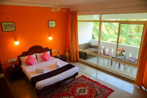 1 dormitorio con 1 cama con paredes de color naranja y ventana en Ocean Bay Ayurvedic Beach Resort, en Kovalam