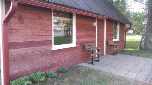 a building with two benches and a window at Kempings Mežmalas in Usma