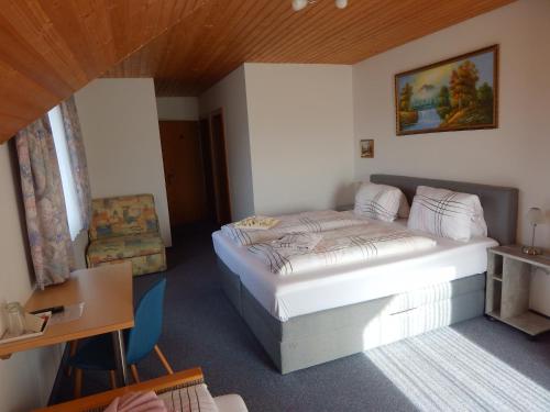 a bedroom with a bed and a desk and a chair at Pension-Ferienwohnung Rotar in Faak am See