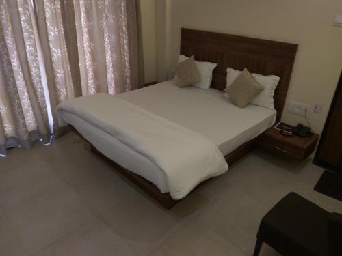 a bedroom with a bed with white sheets and pillows at Manasi Pride in Satara