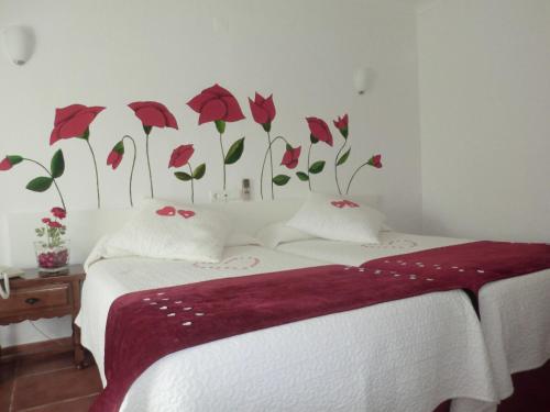 a bedroom with a bed with red flowers on the wall at Varandas de Alter Hotel & SPA in Alter do Chão