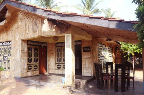 a small wooden house with a table and chairs at Scoop Cabana Kitesurfing in Kalpitiya