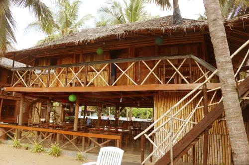 a building with a straw roof and a table and chairs at Scoop Cabana Kitesurfing in Kalpitiya