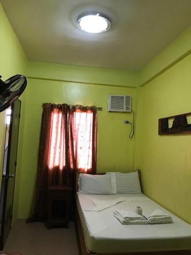 a small bedroom with a bed with a window at Luis Bay Travellers Lodge Coron in Coron