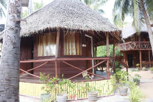 a hut with a straw roof and a palm tree at Scoop Cabana Kitesurfing in Kalpitiya