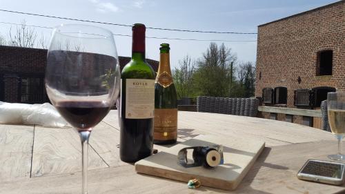 two bottles of wine sitting on a table with a glass at Guesthouse Biolleke in Boutersem