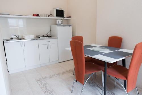 a kitchen with a table and orange chairs at MainStreet apartman in Subotica