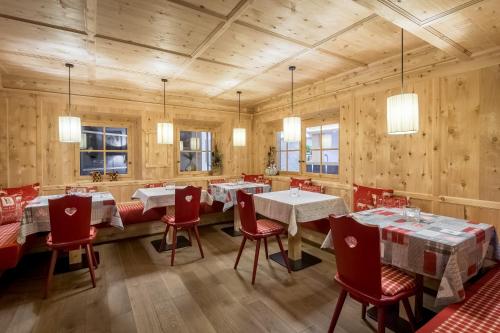 un restaurante con paredes de madera, mesas y sillas rojas en Albergo Posta Pederoa, en La Valle