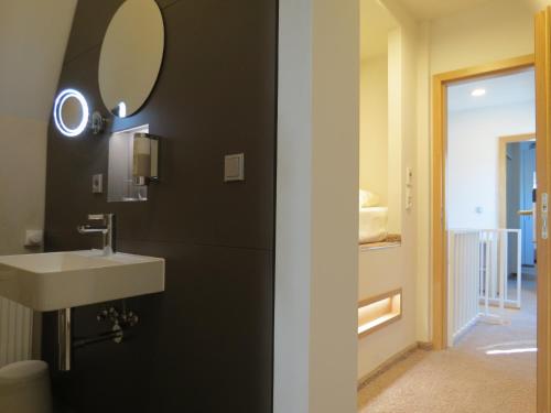 ein Bad mit einem Waschbecken und einem Wandspiegel in der Unterkunft Hotel Neuthor in Ulm