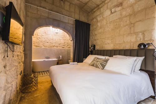 a bedroom with a large bed and a bath tub at Talbot & Bons Bed & Breakfast in Gudja
