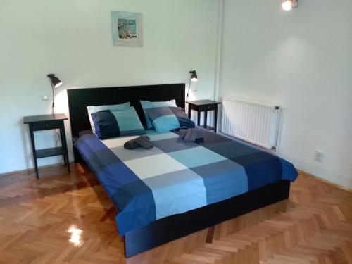 a blue and white bed in a room with two tables at Nia Apartment in Jadranovo