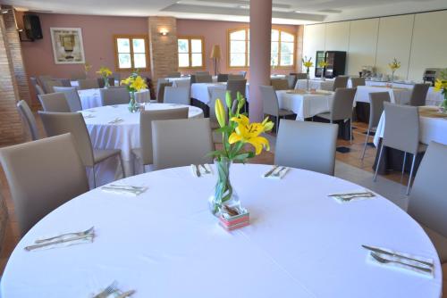 a dining room with white tables and chairs with flowers on them at Jardines de La Santa in Totana