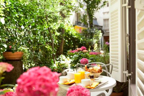 einen Tisch mit Speisen, Getränken und Blumen auf einer Terrasse in der Unterkunft Le Hameau de Passy in Paris