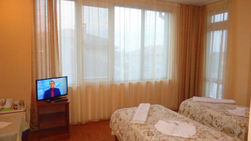 a hotel room with two beds and a television at Matev Hotel in Burgas City