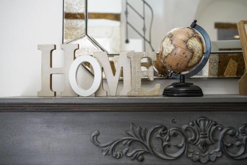 a sign that says home on a shelf with a globe at Dimora Maestà in Putignano
